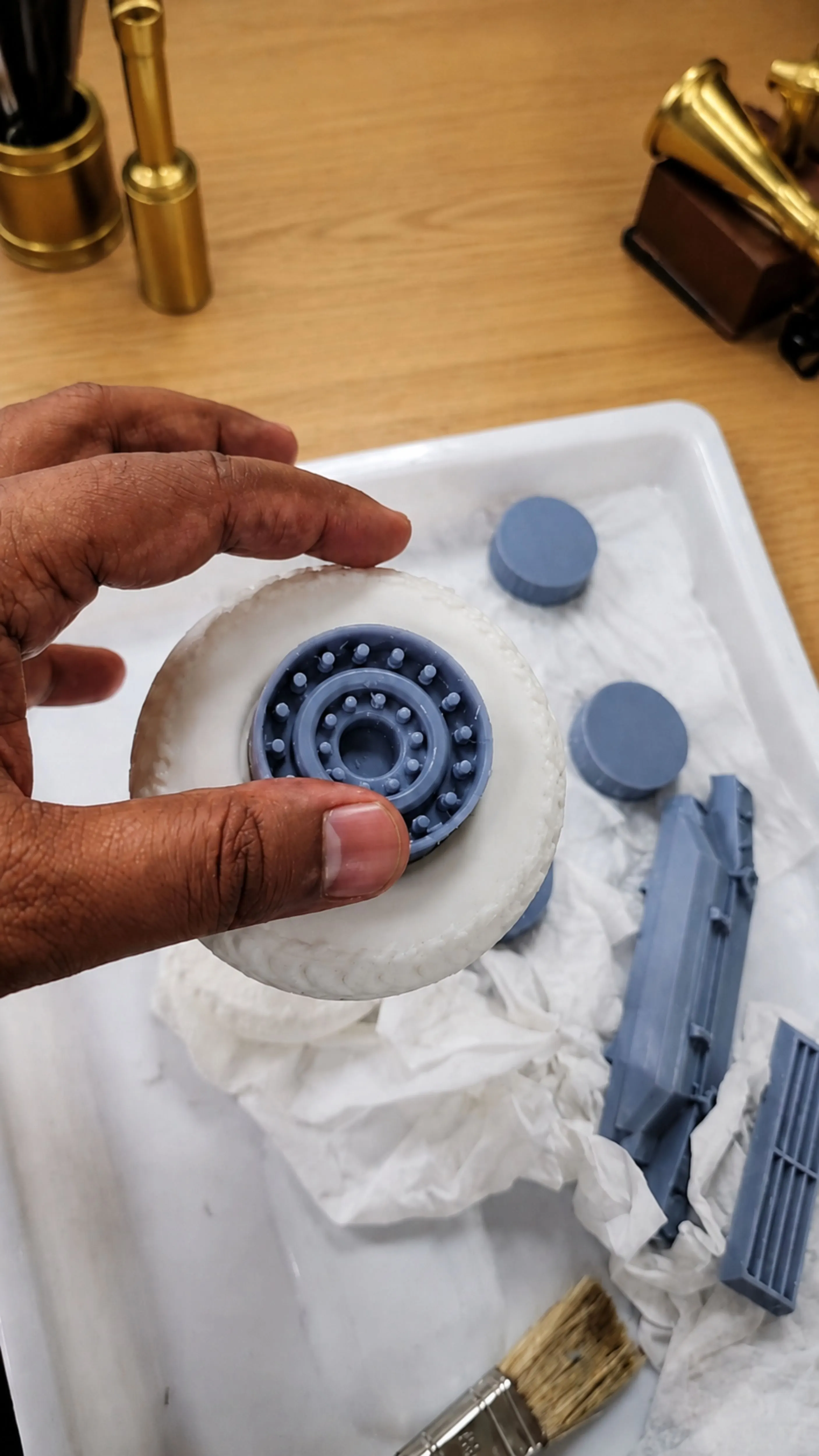 Hand holding a finished wheel hub showing the layered SLA-printed detail before bonding to the tyre