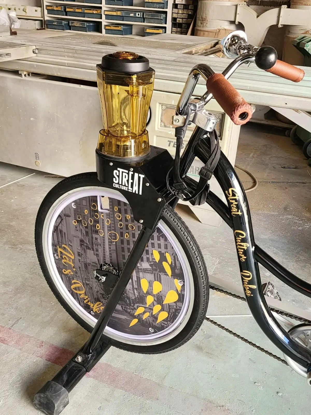 The StrEat Culture blender bike in the NSQD workshop, amber blender jug mounted on the head unit, gold lettering down the tube