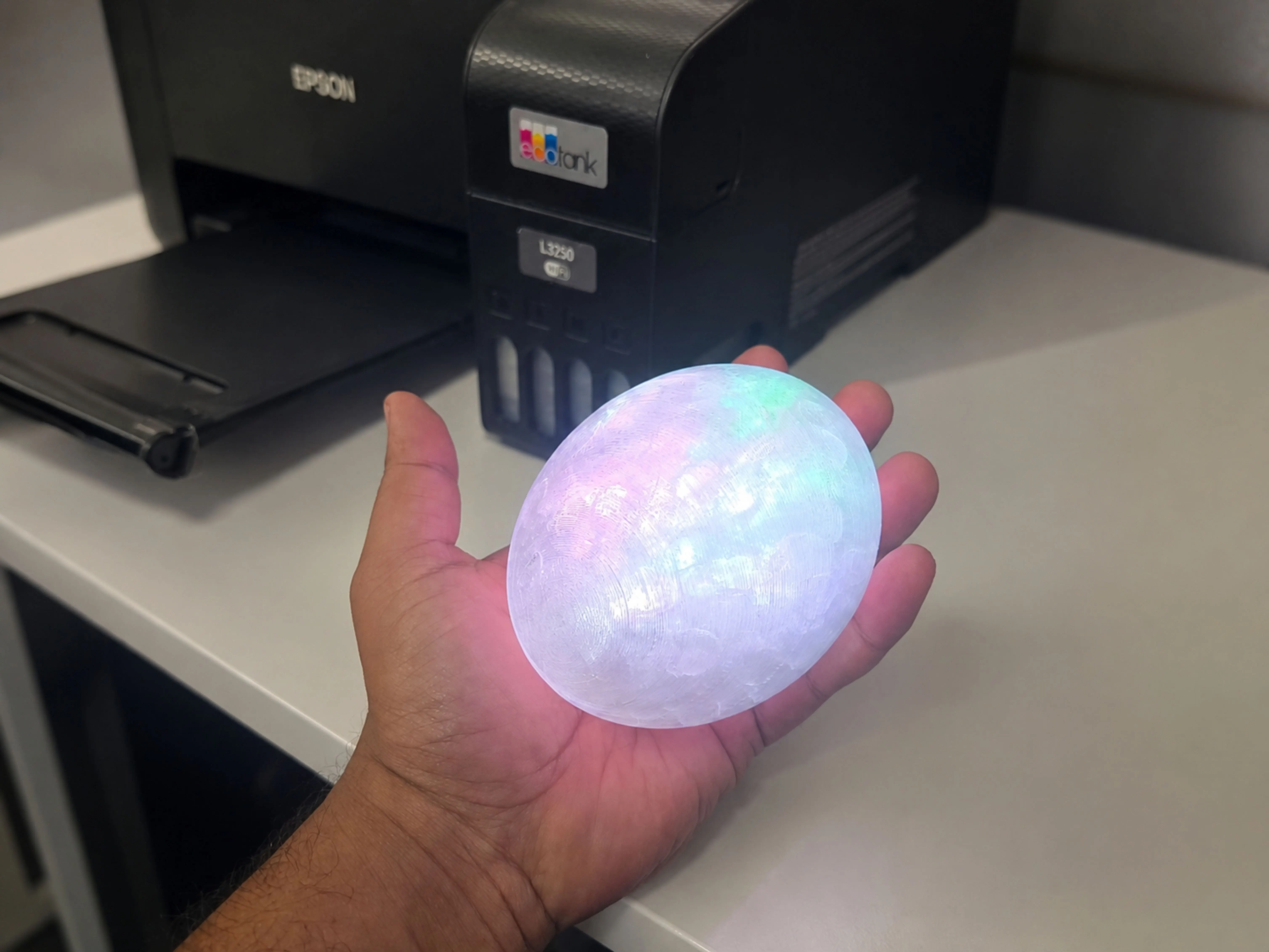 Translucent 3D-printed ember shell powered up in the workshop, with internal RGB lighting visible through the print layers