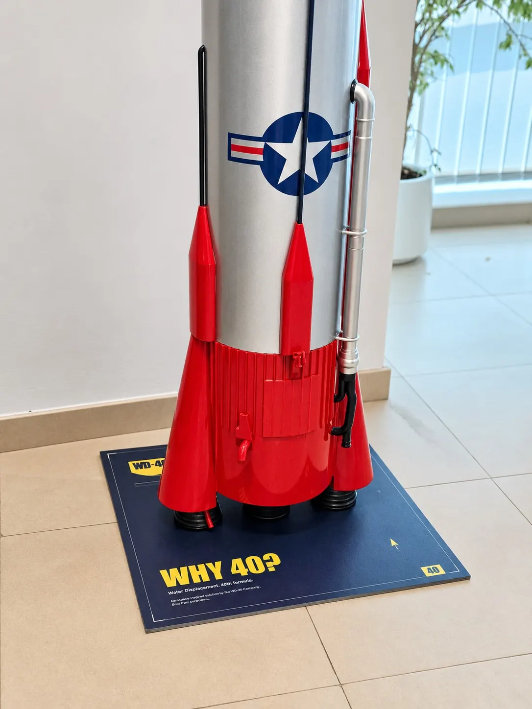 Close-up of the red boosters, fins, skirt and chrome fuel line on the WHY 40? plinth