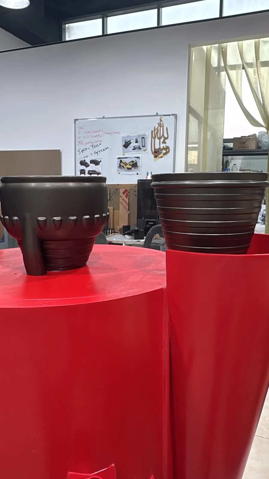 Two raw FDM-printed engine bells resting on red-painted booster sections in the NSQD workshop