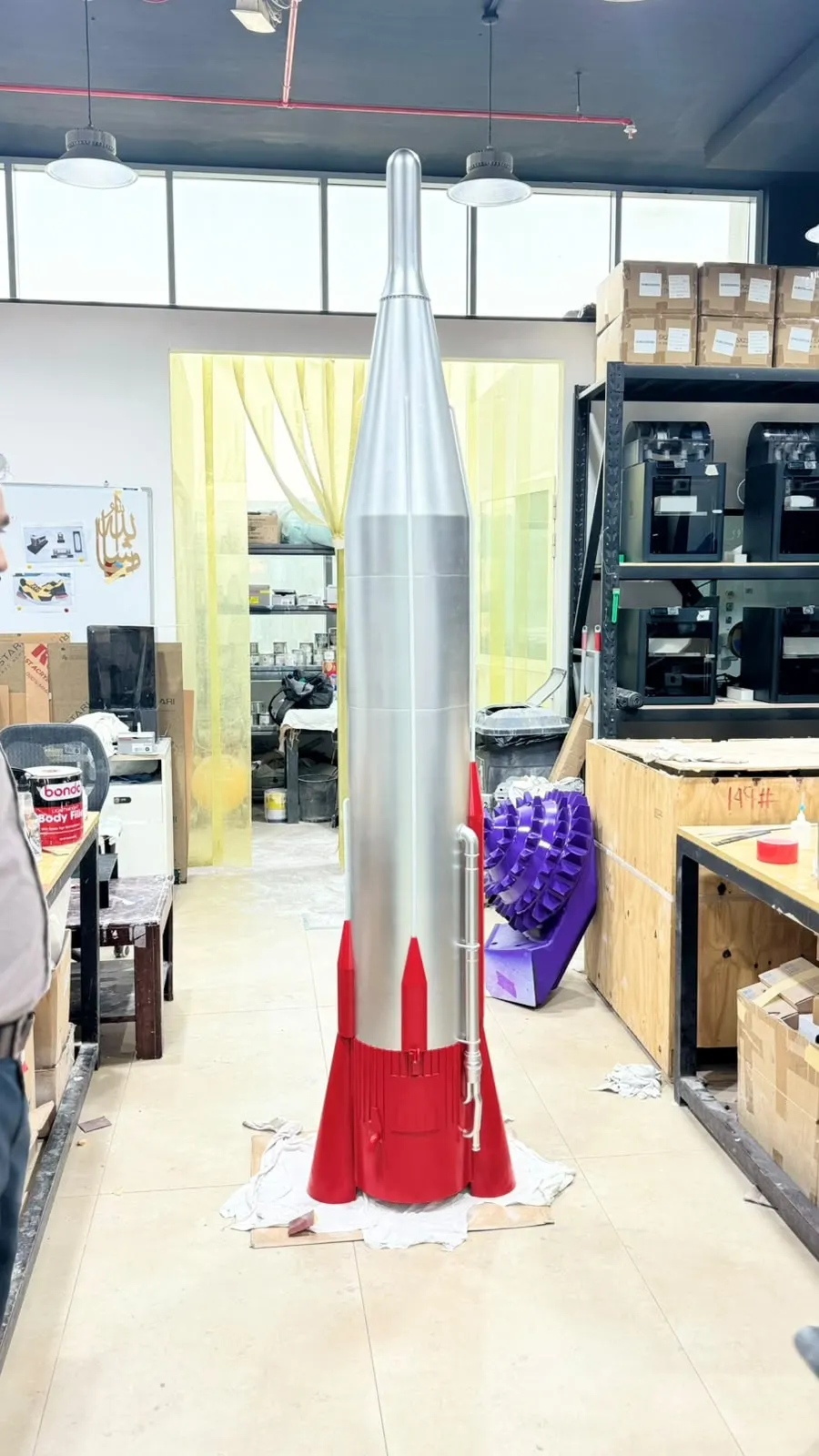 The assembled 2.5 m Atlas replica standing in the NSQD Dubai workshop with the Bambu Lab printer farm behind it